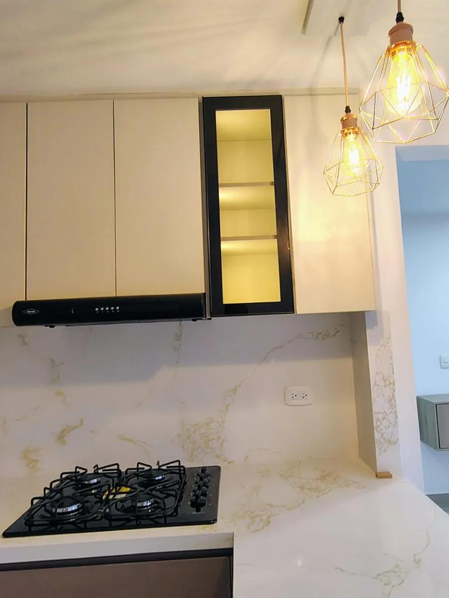Vitrina con luz: Vitrina de perfil negro con luz cálida y campana integrada en los muebles altos.