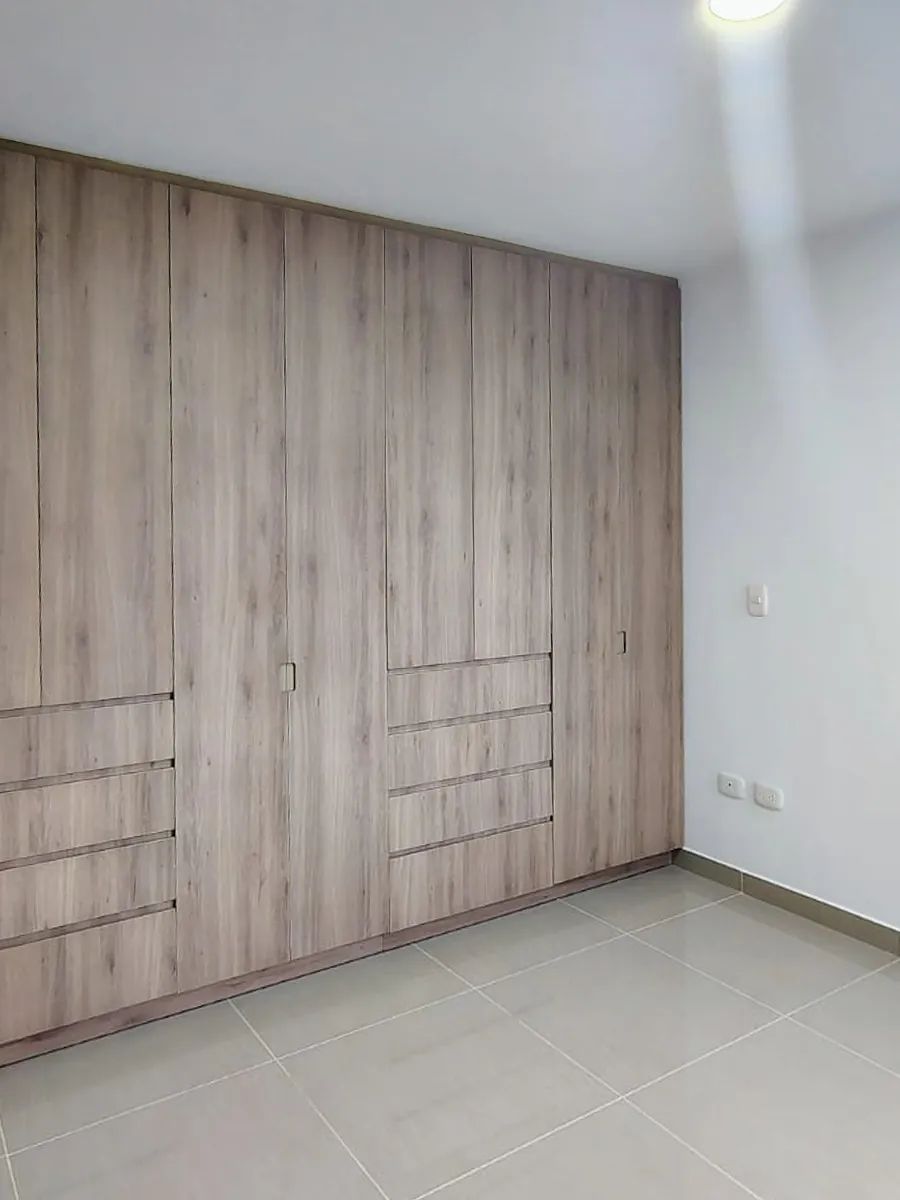 Closet de pared a pared: Puertas de piso a techo en madera clara, con cajoneras a los dos lados.