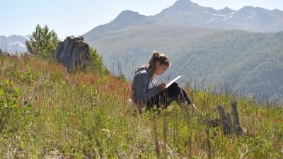 Girl journaling in a field a Mount St. Helens