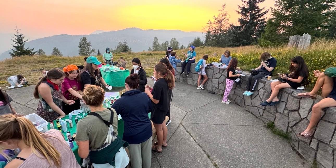 GeoGirls creating art outside at a picnic table during sunset.