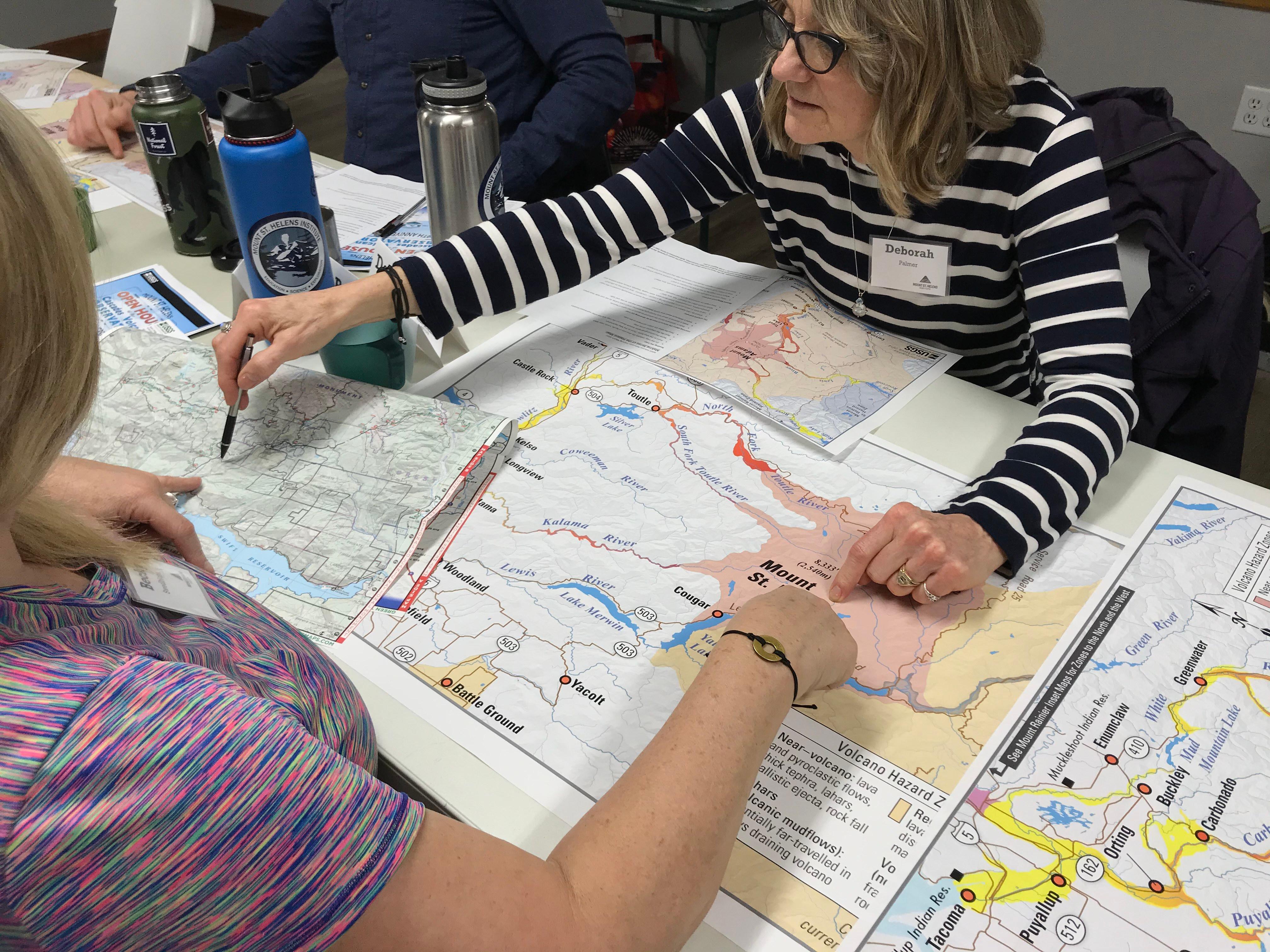 People looking at maps on a table learning about Mount St. Helens