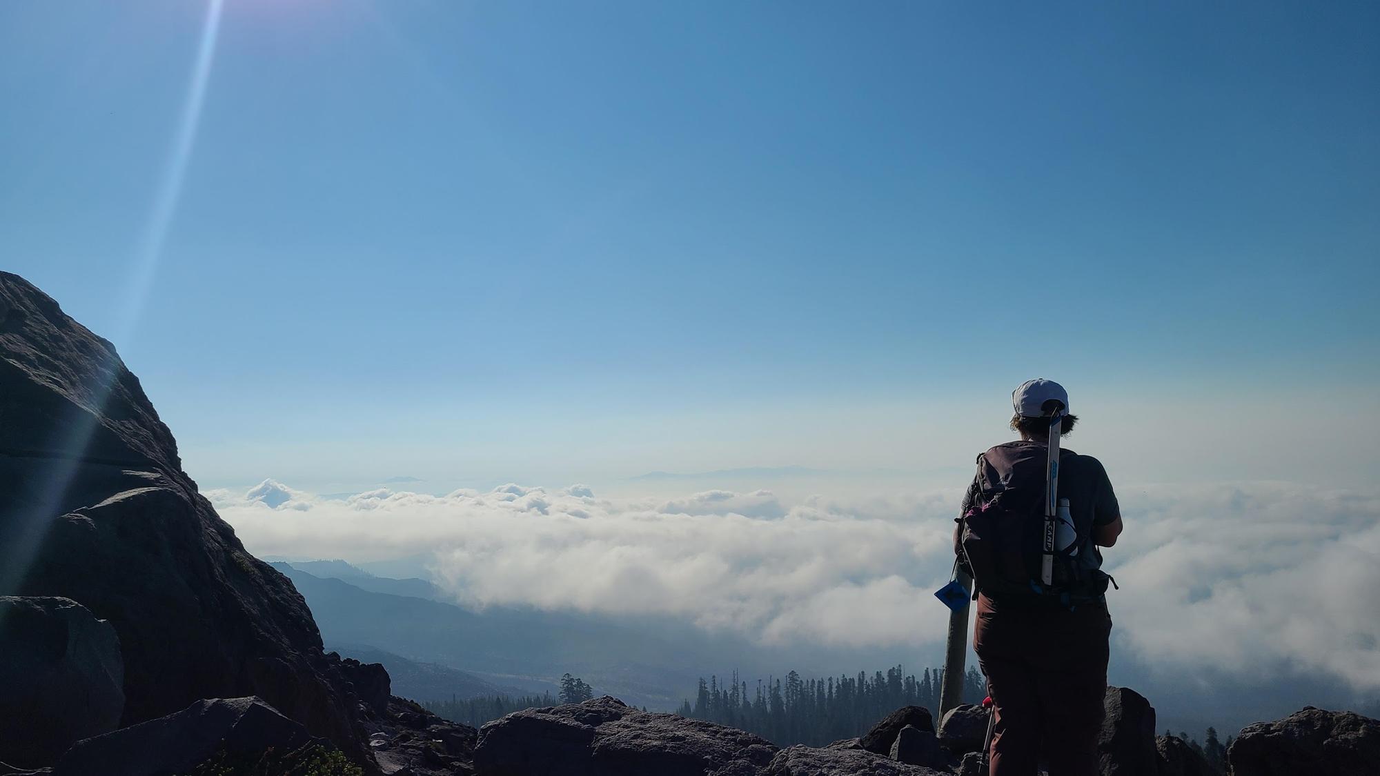 Person standing on Mount St. Helens looking out over the clouds.