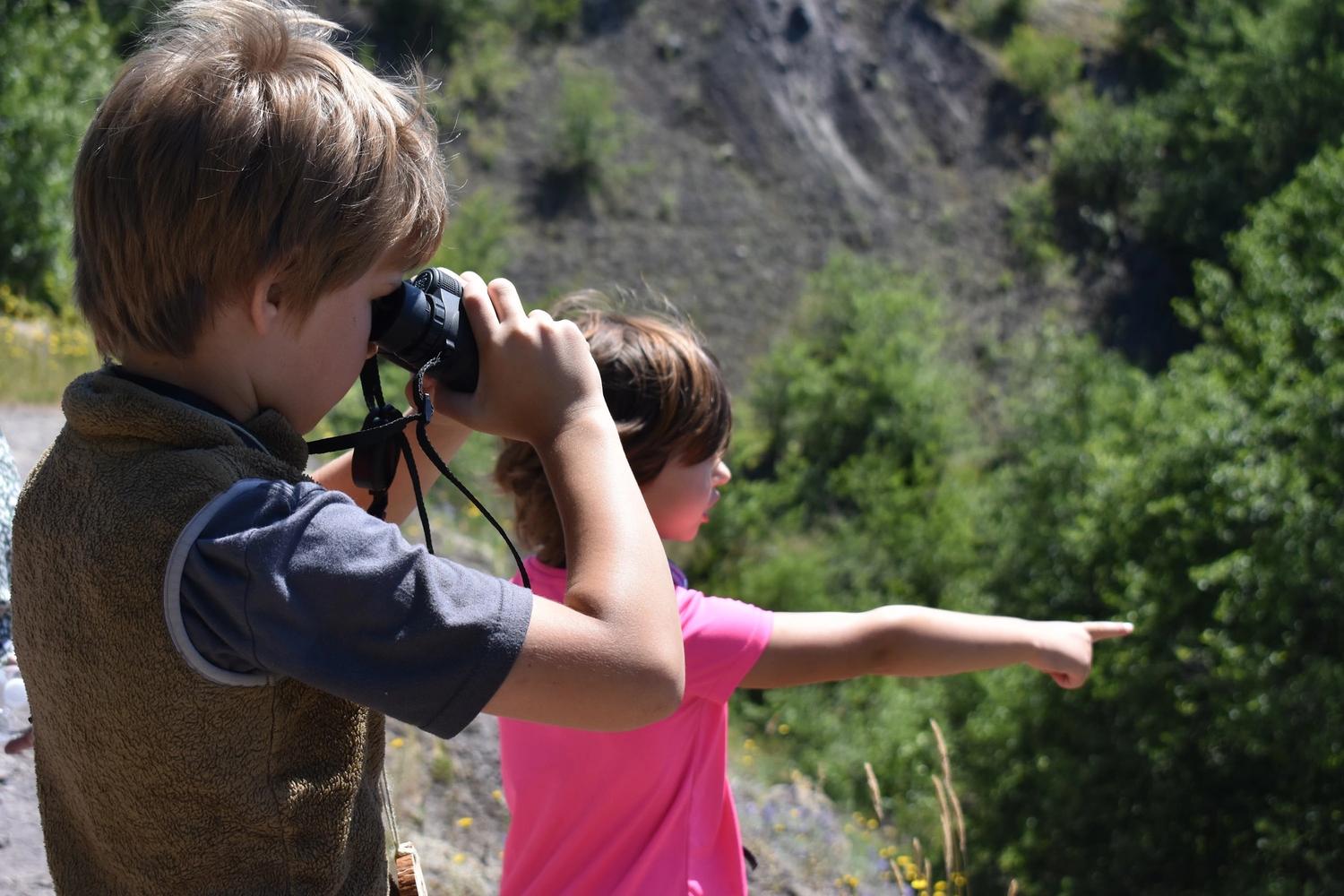 Young people looking through binoculars at an interesting view at the Hummocks trail near Mount St. Helens