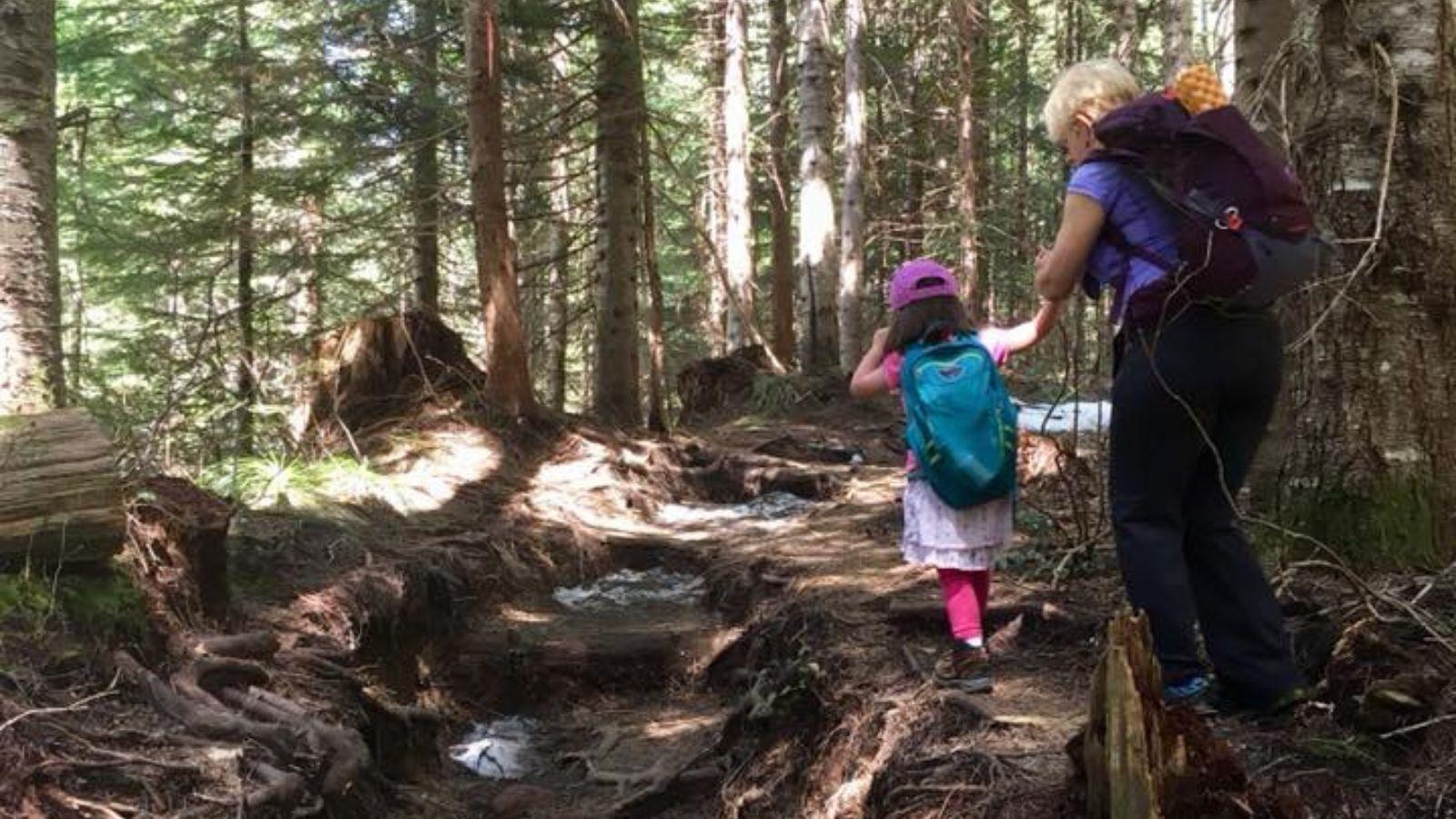 A woman and a child walk through the forest