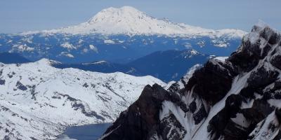 Snow-capped Mount Rainier looms on the horizon beyond the crater rim of Mount St. Helens