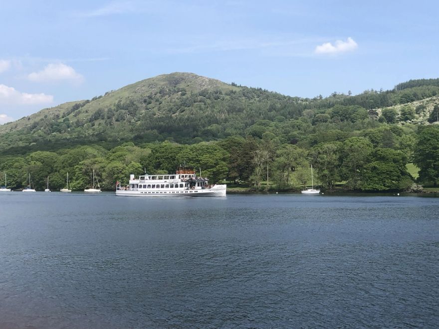 Boat on the Windermere Lake with green hills in the background