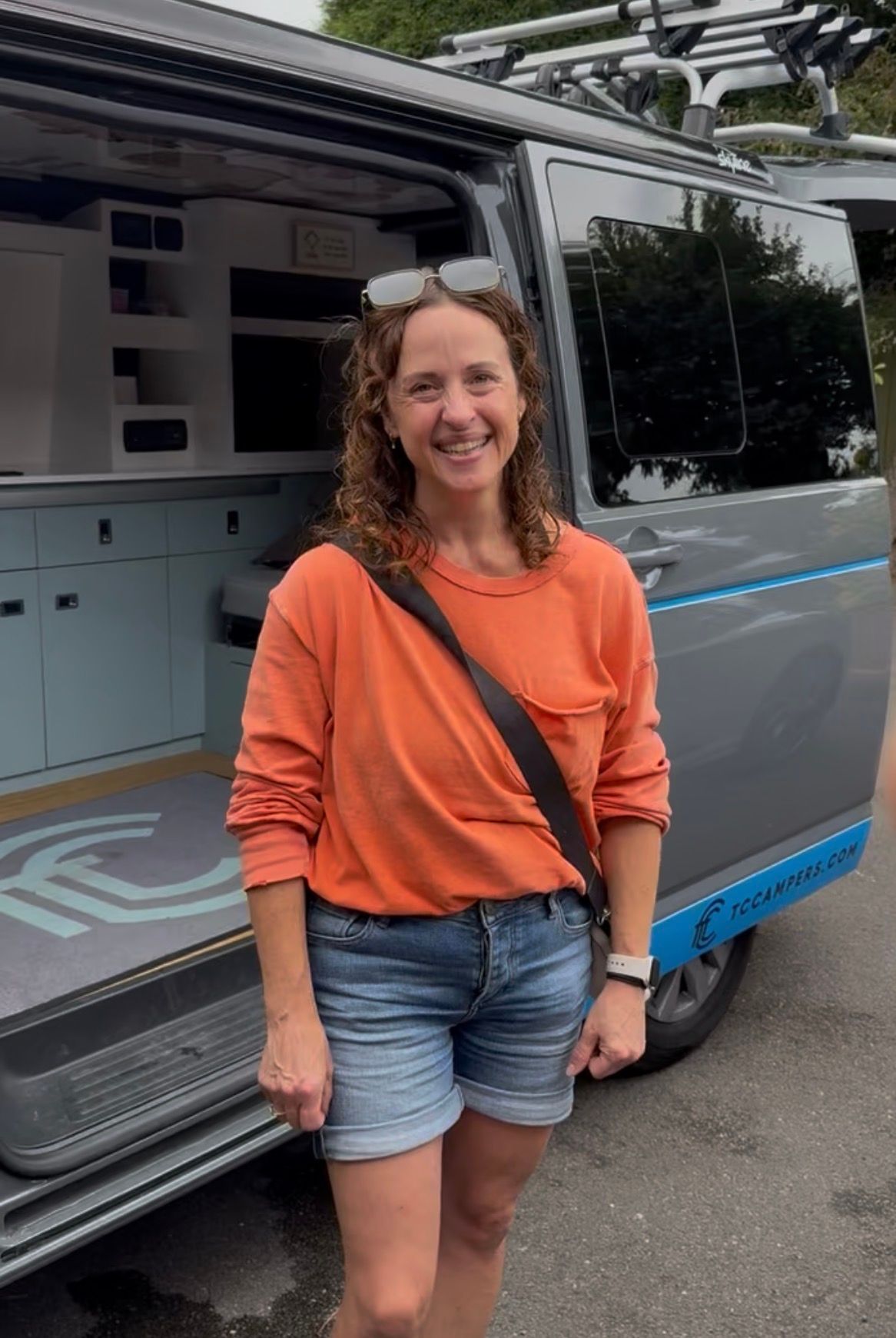 Customer standing by the campervan and smiling