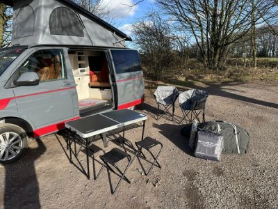 Fenyx parked up with the camping table, chairs and awning bag set out beside it