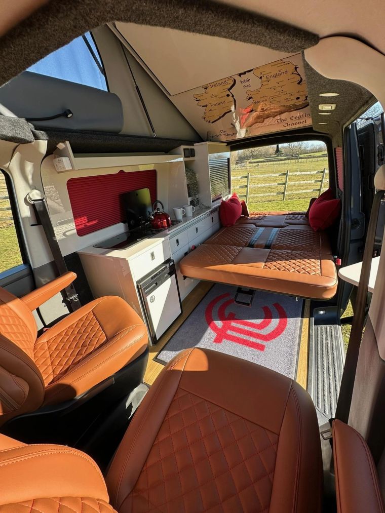 Inside Fenyx, the tan leather seats and white kitchen with the bed folded out