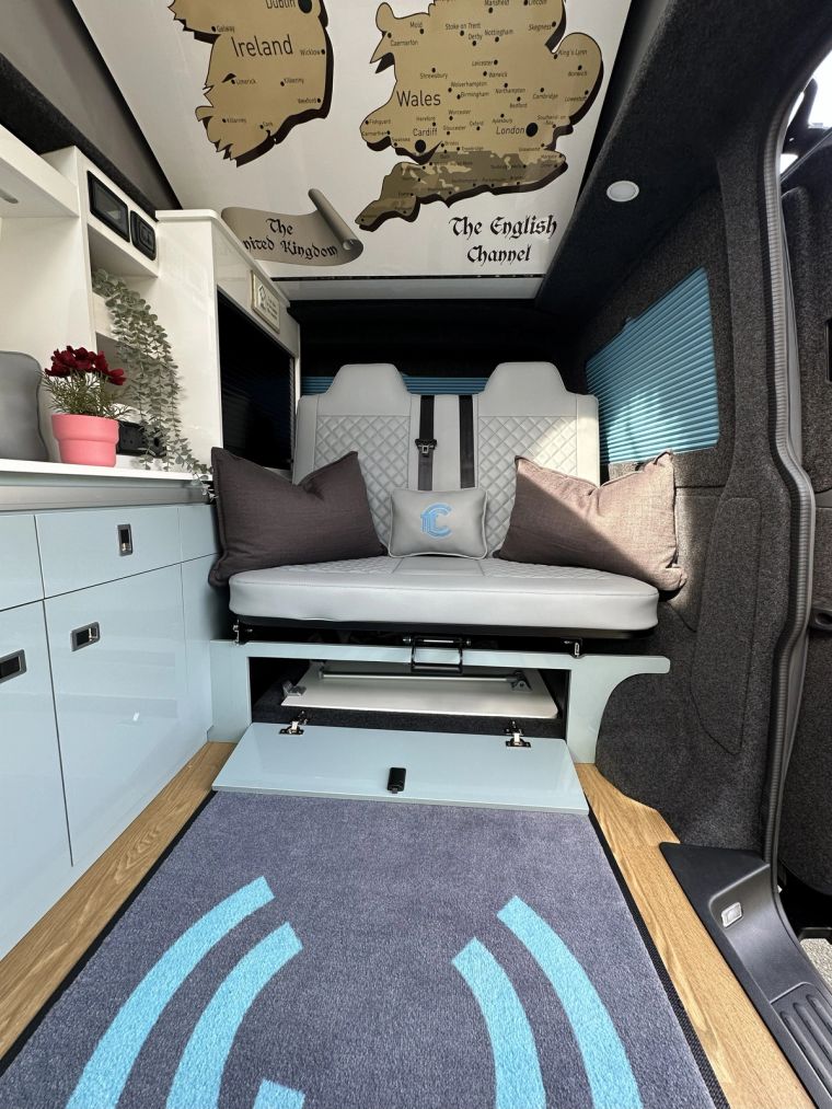 Inside Enola, the blue kitchen and rock and roll bed beneath a UK map roof print