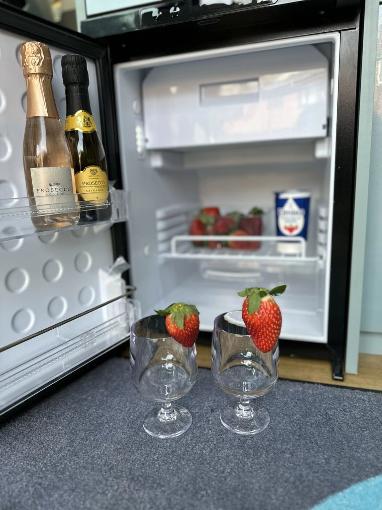 The fridge stocked with prosecco and strawberries, with two glasses ready