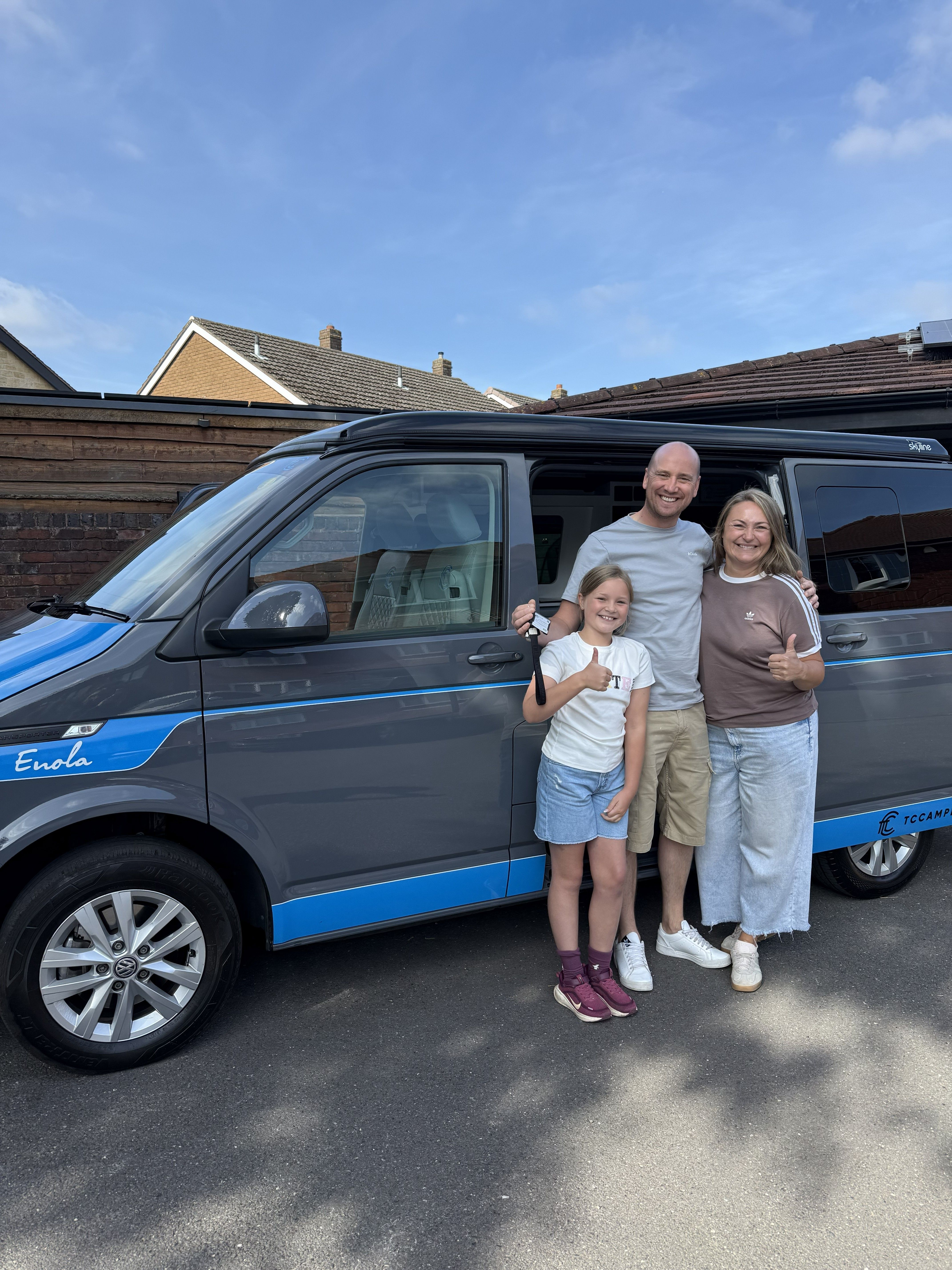 Nicola and her family standing by the campervan Enola and smiling