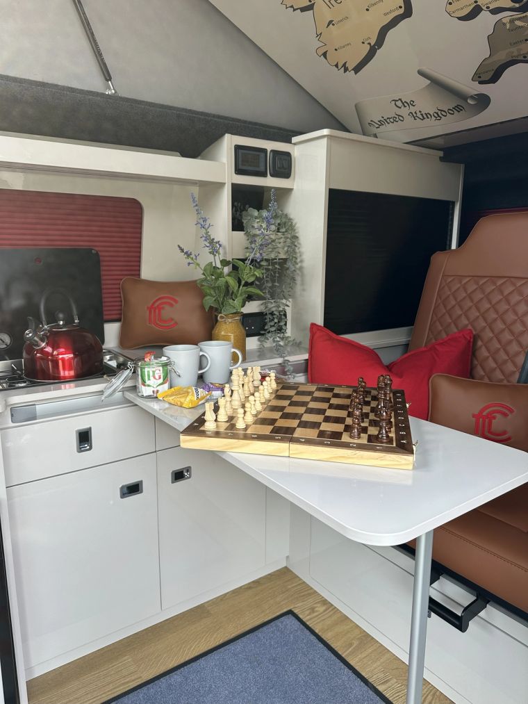 A chess board on the foldable table inside Fenyx, with the kettle on the hob
