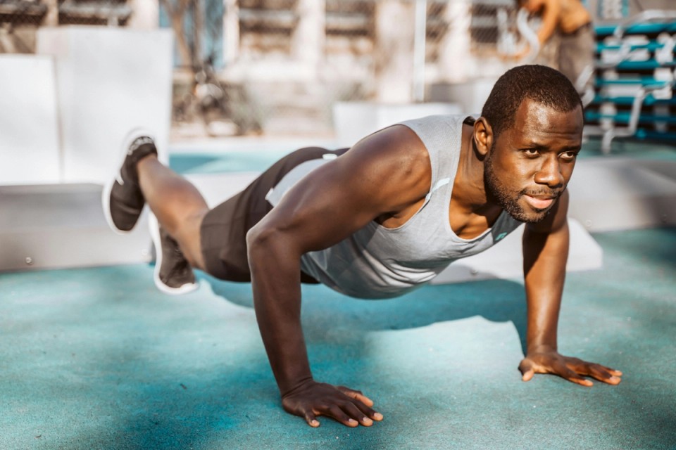 Athlete performing a push-up outdoors using only body weight, demonstrating functional strength, whole-body coordination, and natural movement without relying on gym machines or external loads.