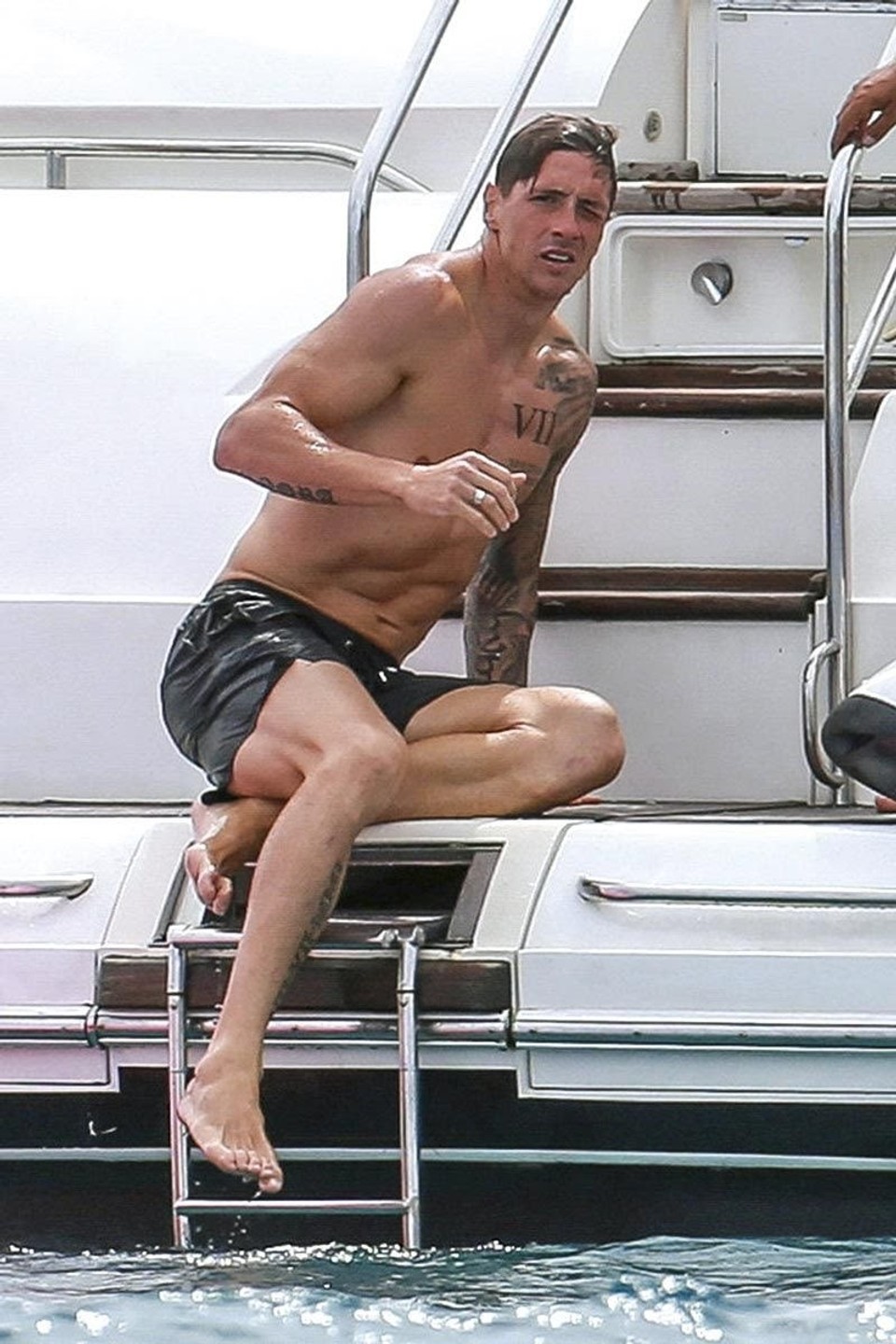 Fernando Torres climbing onto a boat barefoot, showing the visible tendons and foot structure associated with world-class footballers explored in this article.