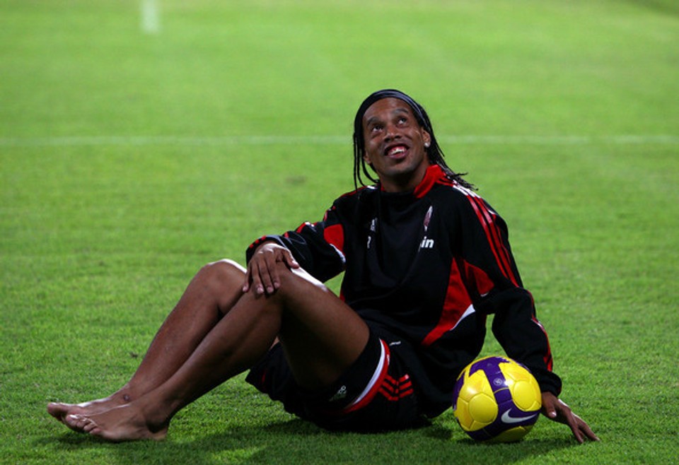 Ronaldinho sitting barefoot on a football pitch with a ball, illustrating the natural foot function, relaxed movement, and athletic qualities discussed in this article.