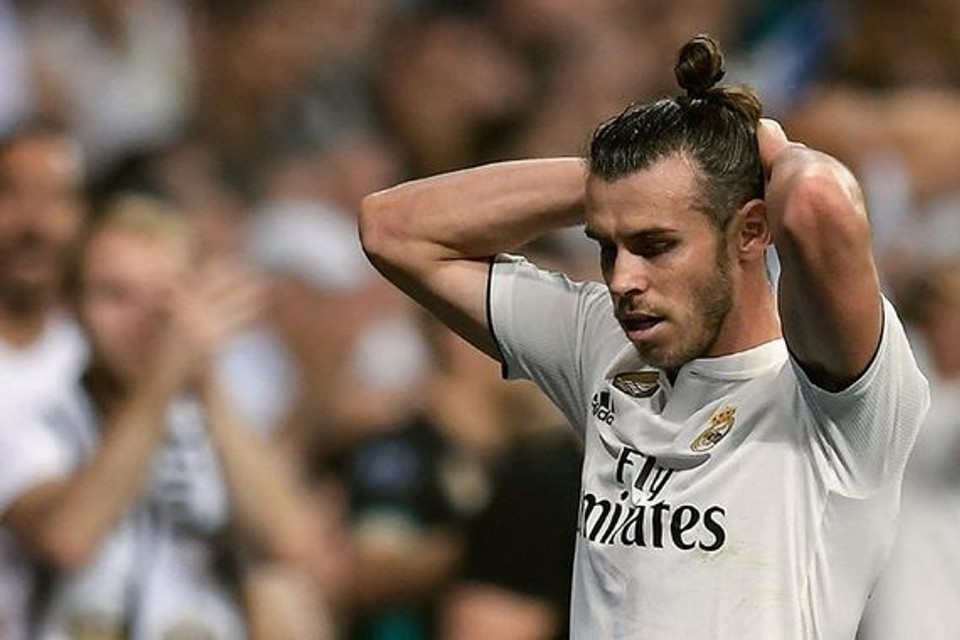 Professional footballer Gareth Bale stands on the pitch with his hands behind his head after a match, reflecting the frustration and physical toll that injuries can have on elite athletes.