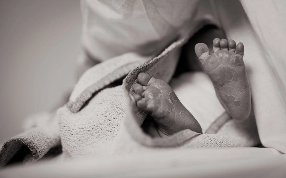 Close-up of a newborn baby's feet resting beneath a blanket, illustrating the innate qualities of early human development and natural athletic potential.