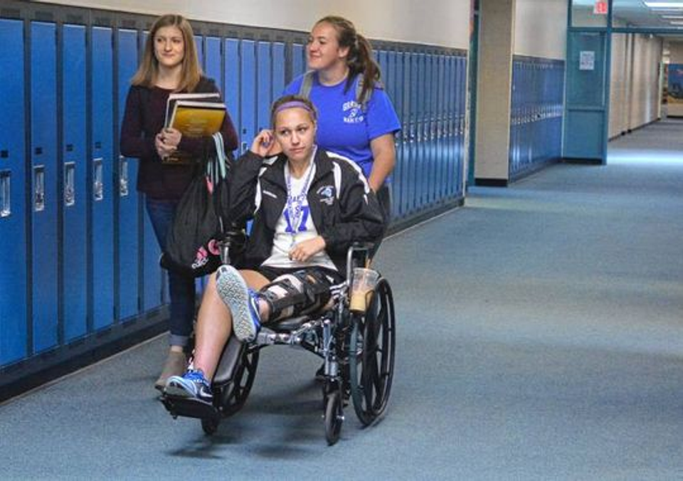 Young athlete in a wheelchair wearing a knee brace after a serious leg injury, illustrating the rise of severe youth sports injuries discussed in this article.