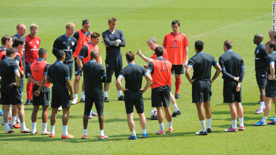 England national team players gather around their coach during a training session, representing the modern coaching environments and football culture discussed in this article.