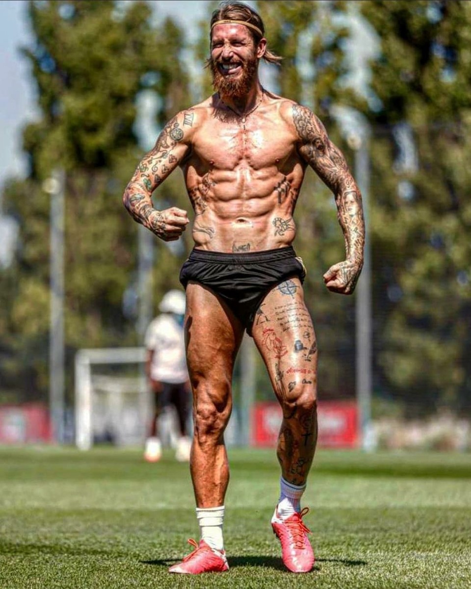 Sergio Ramos standing shirtless on a football pitch, displaying a muscular physique while celebrating during a training session.