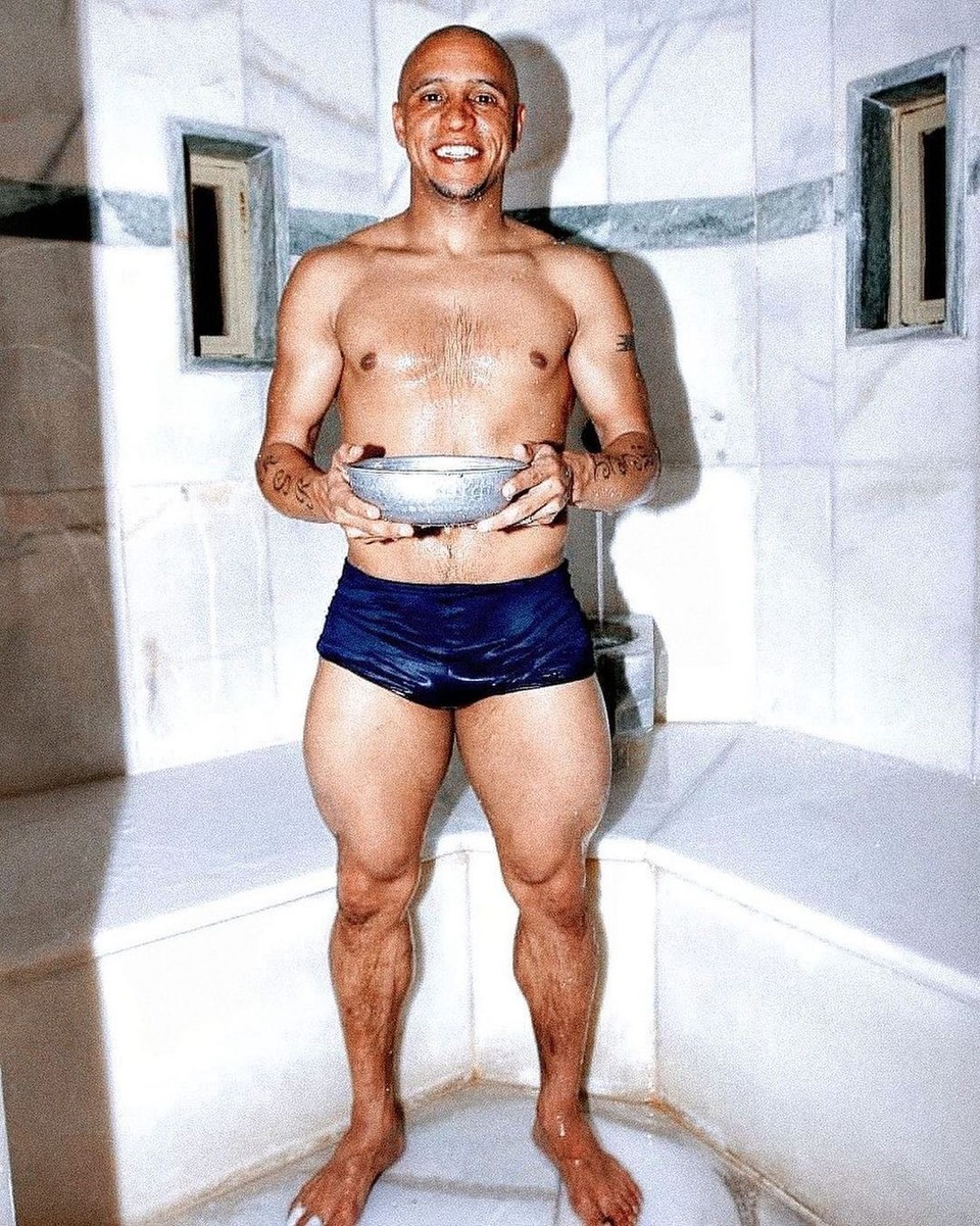 Former footballer Roberto Carlos standing barefoot, displaying the lean, powerful physique and lower-body development characteristic of many world-class footballers.