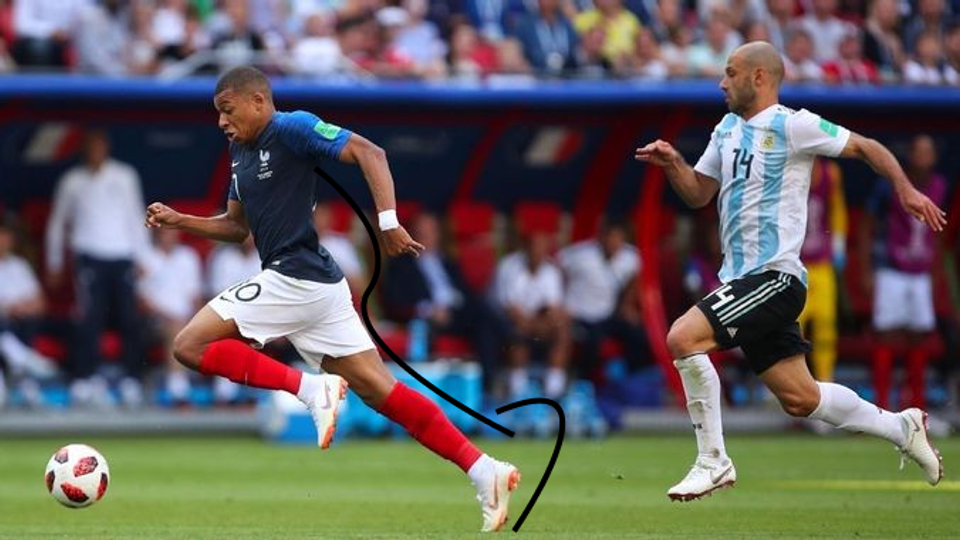 Professional footballer Kylian Mbappé sprints at full speed during a match with long, powerful strides, illustrating the integrated whole-body mechanics behind world-class acceleration and speed.