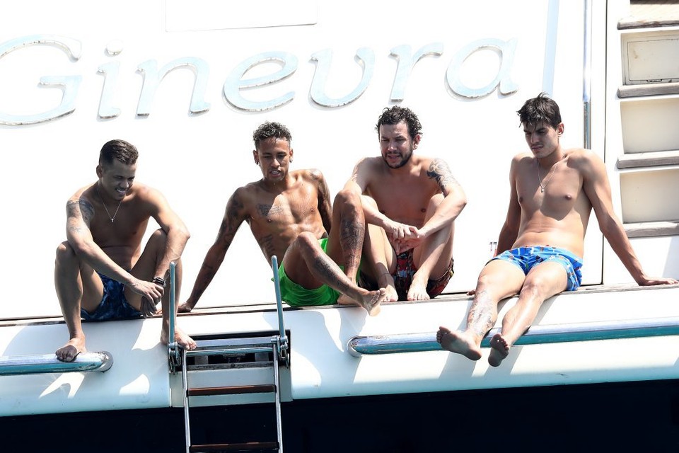 Professional footballers relaxing outdoors in the sun on a boat, illustrating the importance of natural sunlight and outdoor living discussed in this article.