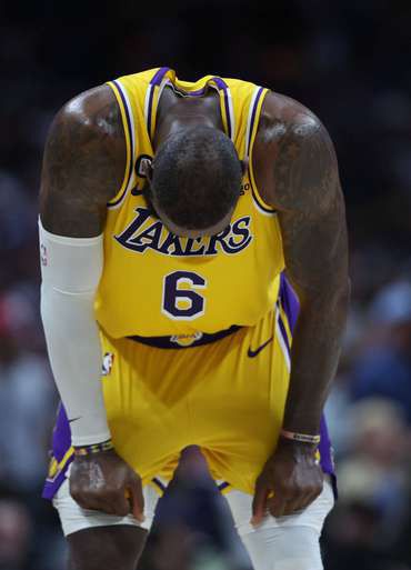 LeBron James, in a yellow Lakers number 6 jersey, bent over with his hands on his knees.