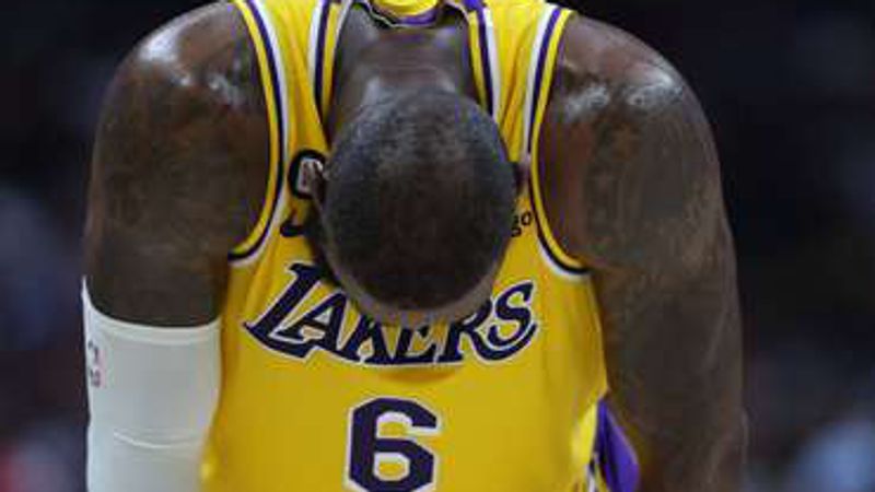 LeBron James, in a yellow Lakers number 6 jersey, bent over with his hands on his knees.