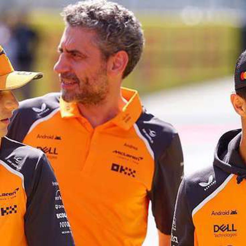 Oscar Piastri, team principal Andrea Stella and Lando Norris talking, all in orange McLaren team clothing.