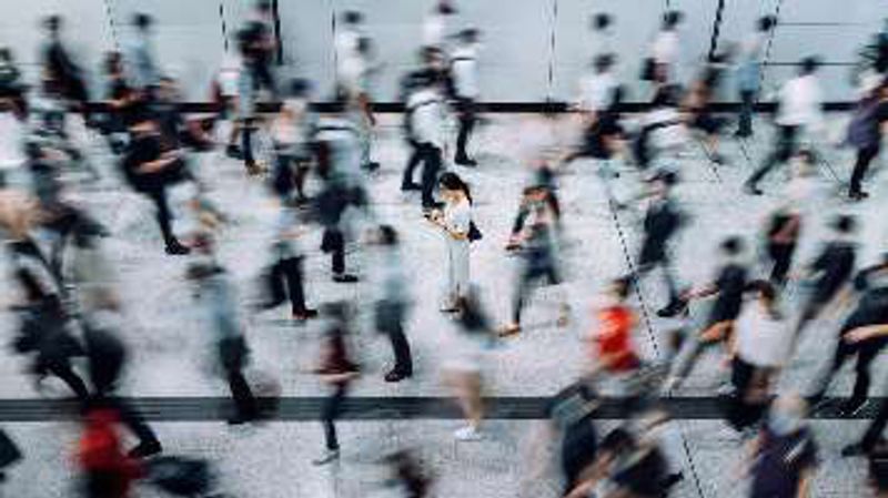 A crowd of commuters blurred in motion around one person standing still.