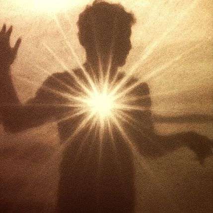 A sepia silhouette of a person with a burst of light shining from their chest.