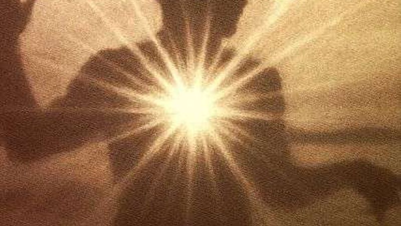 A sepia silhouette of a person with a burst of light shining from their chest.
