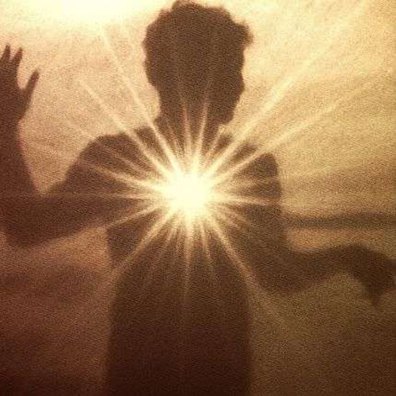 A sepia silhouette of a person with a burst of light shining from their chest.