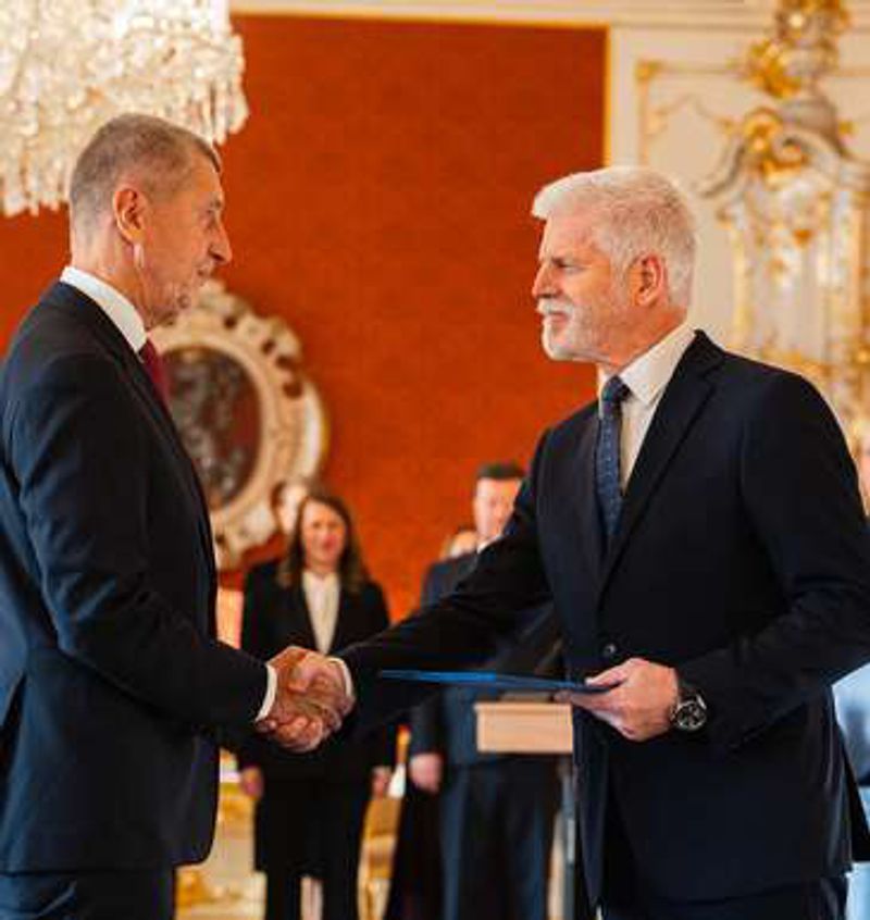Andrej Babiš shakes hands with President Petr Pavel in a gilded hall at Prague Castle.