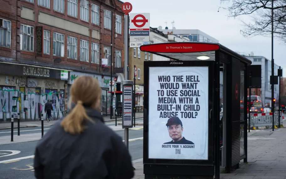 A woman walks past a London bus stop poster of Elon Musk reading “Who the hell would want to use social media with a built-in child abuse tool?”