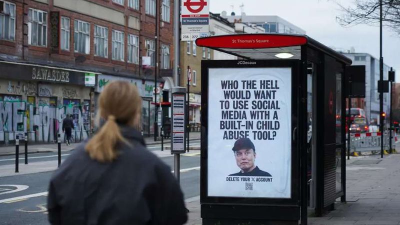 A woman walks past a London bus stop poster of Elon Musk reading “Who the hell would want to use social media with a built-in child abuse tool?”