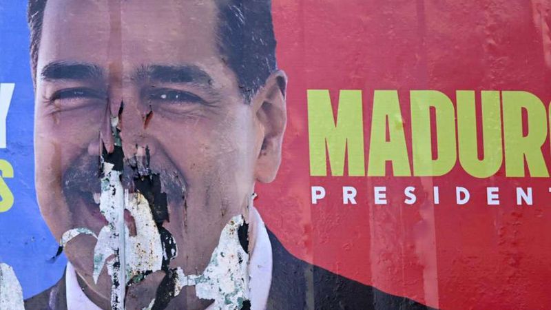 A torn and burned election billboard showing Nicolás Maduro's face beside the words “Maduro Presidente”.