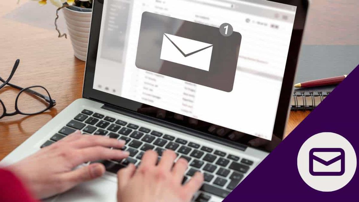 Person typing on a laptop with an email notification icon, representing a professional meeting follow-up email.