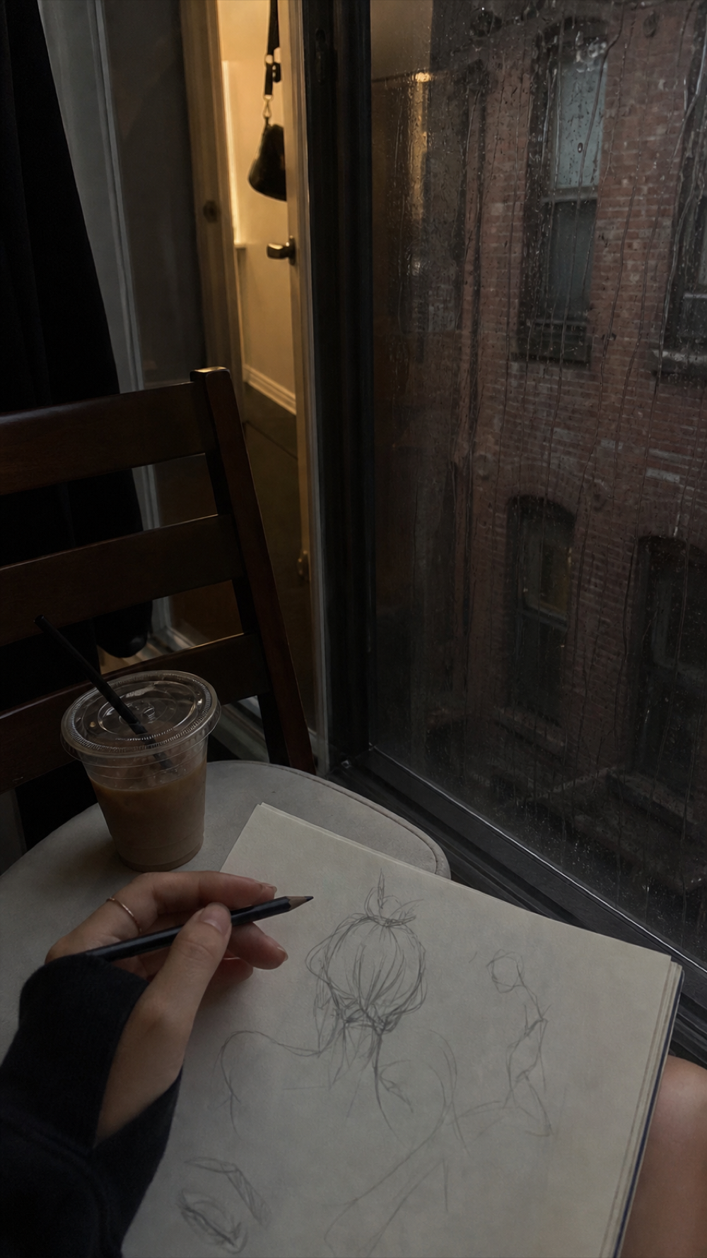 A sketchbook beside a rainy window