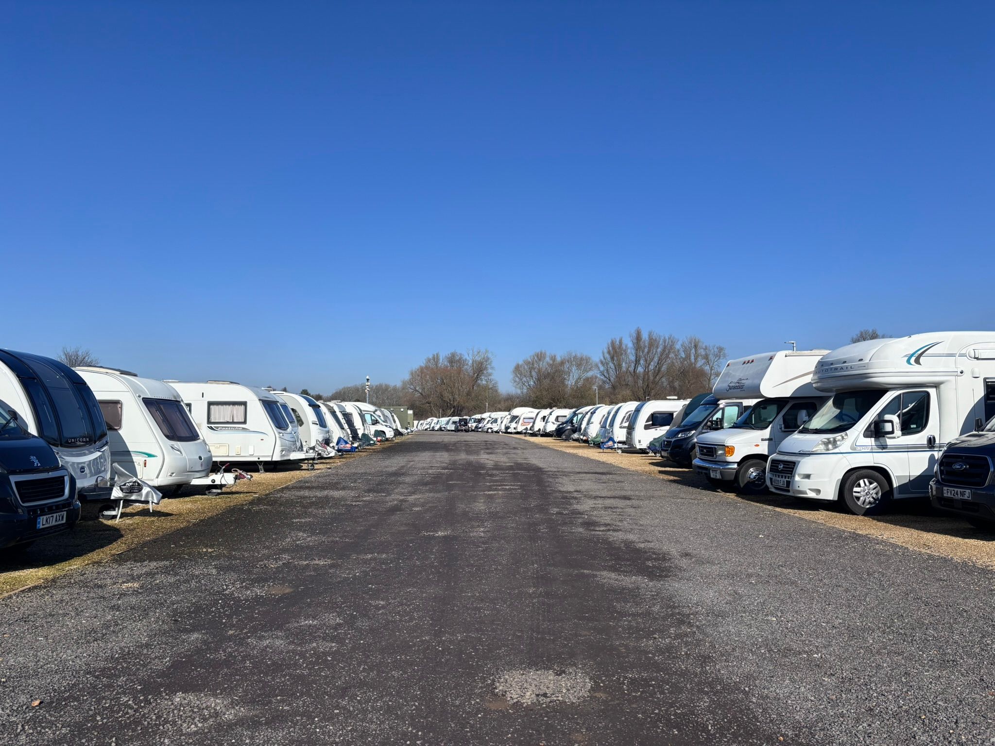 Touring caravans and motorhomes parked in rows on level hardstanding