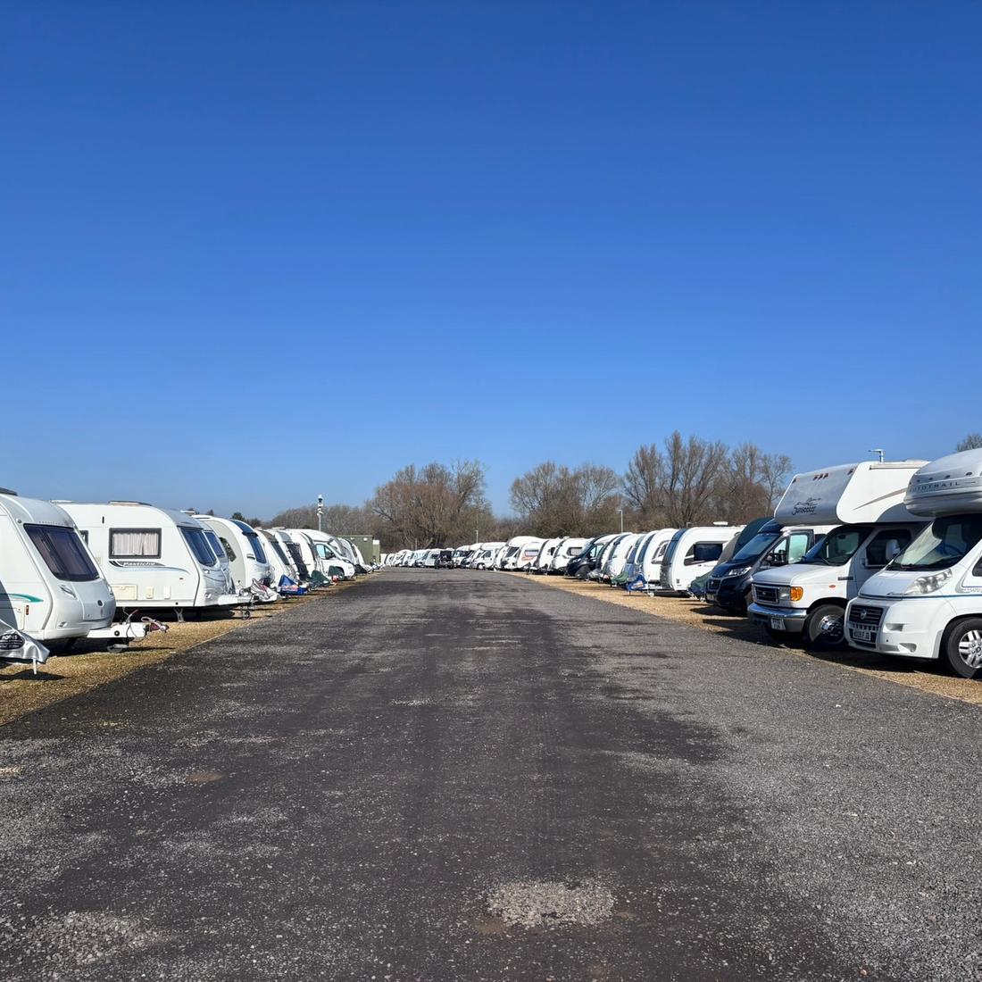 Touring caravans and motorhomes parked in rows on level hardstanding