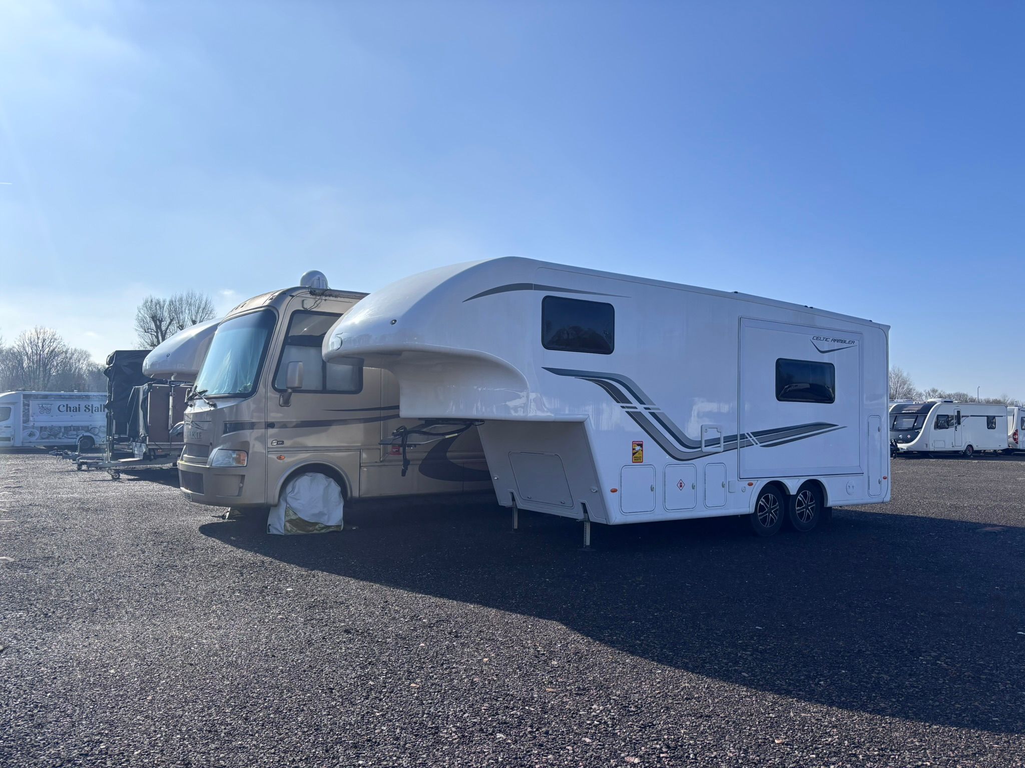 A large American-style RV stored alongside touring caravans