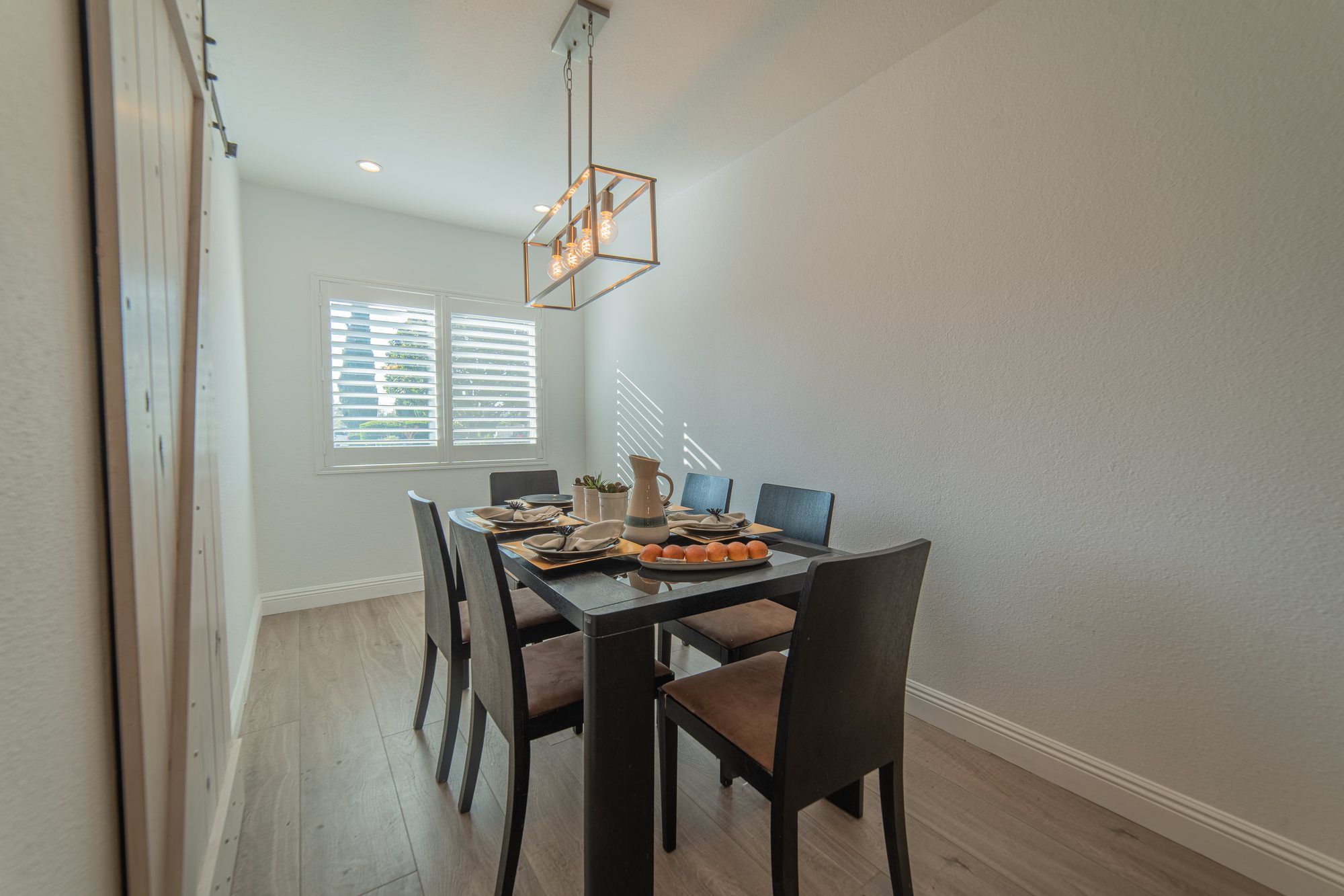 Dark dining table set for six under a lantern chandelier, Anaheim