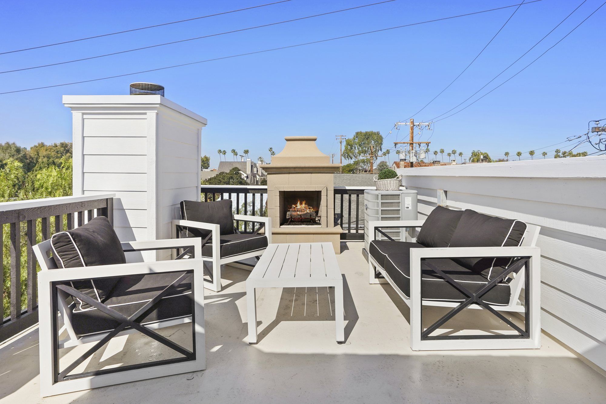 Roof deck with an outdoor fireplace and black-and-white seating, Newport Beach