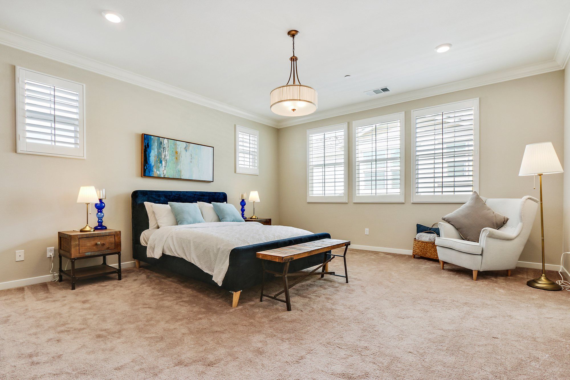 Primary bedroom with a navy upholstered bed and a reading chair, Irvine
