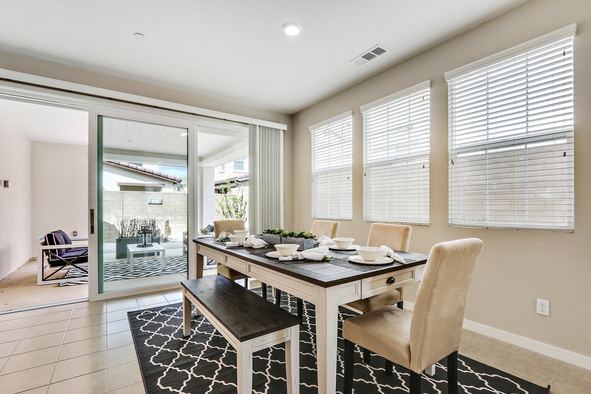 White farmhouse dining table and bench on a navy patterned rug, Irvine