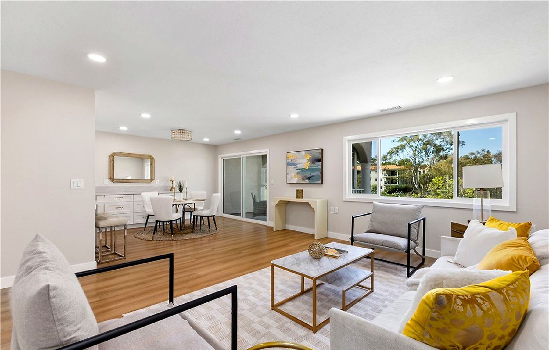 A staged condo living room with white armchairs and yellow pillows