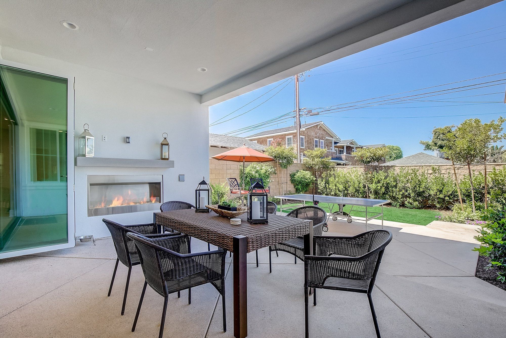 Covered patio with an outdoor dining table beside a linear fireplace, Costa Mesa